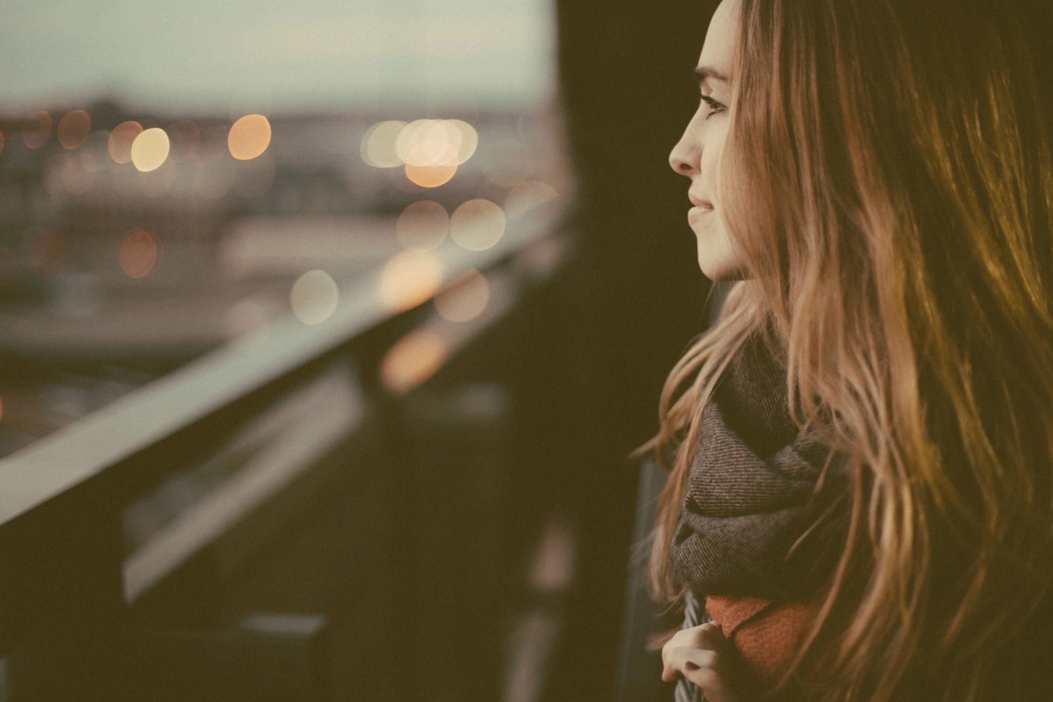 A woman (35&ndash;50) sitting by a window, soft natural light, relaxed but thoughtful expression.