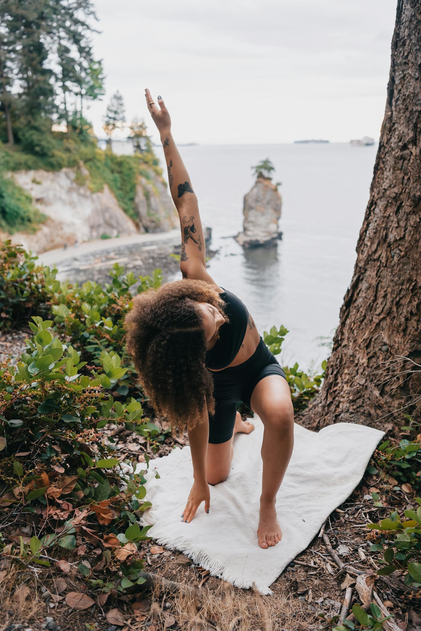 Woman practicing yoga on a cliffside with ocean view, embracing wellness and healthy living.