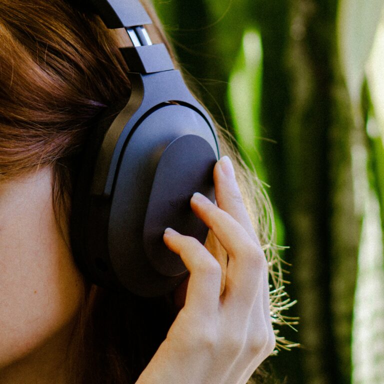 Woman listening to cycle syncing playlists on large earphones