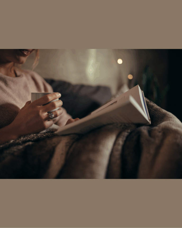 A woman practicing self-care for women by relaxing in the evening, at home with a mug of hot cocoa and a book,