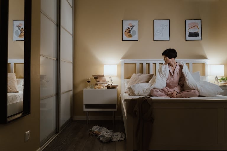 Asian woman in perimenopause, wearing pajamas sitting on bed, unable to sleep