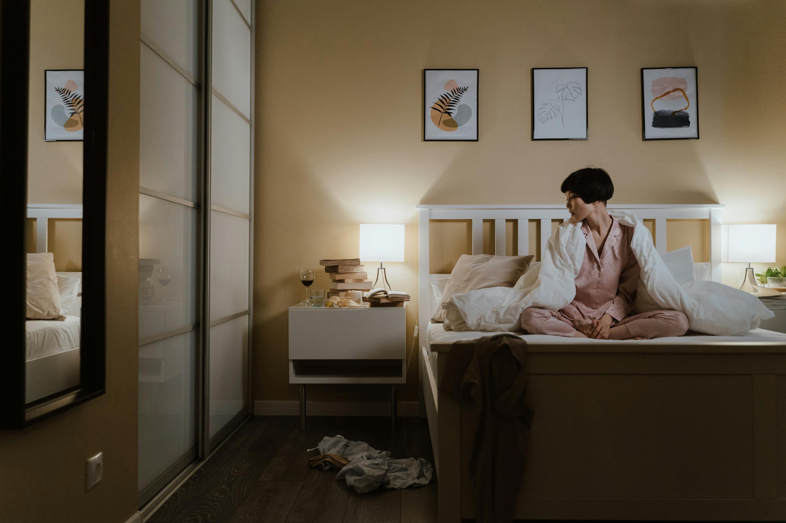 Asian woman in perimenopause, wearing pajamas sitting on bed, unable to sleep