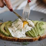 Delicious avocado toast topped with a perfectly poached egg and fresh herbs, ideal for a healthy, high protein meal in midlife.