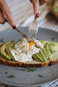 Delicious avocado toast topped with a perfectly poached egg and fresh herbs, ideal for a healthy, high protein meal in midlife.
