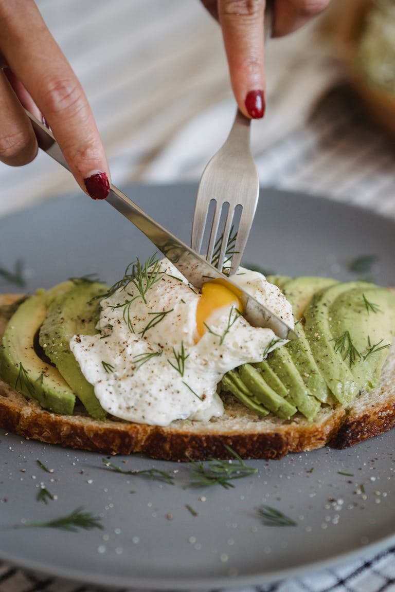 Delicious avocado toast topped with a perfectly poached egg and fresh herbs, ideal for a healthy, high protein meal in midlife.