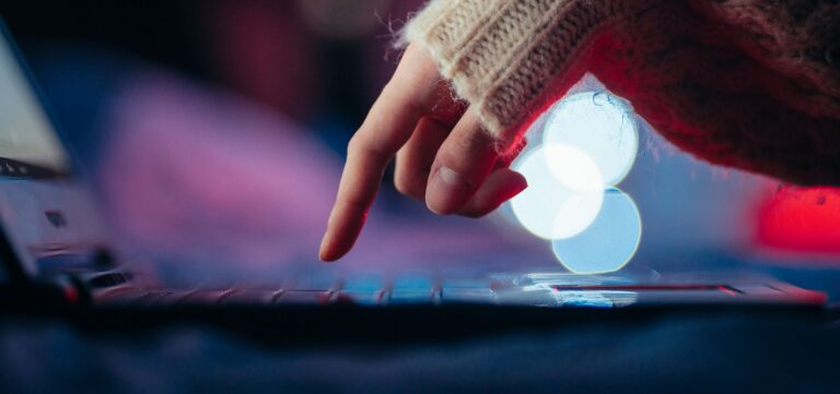 Cozy atmosphere with a hand typing on a laptop surrounded by bokeh lights.
