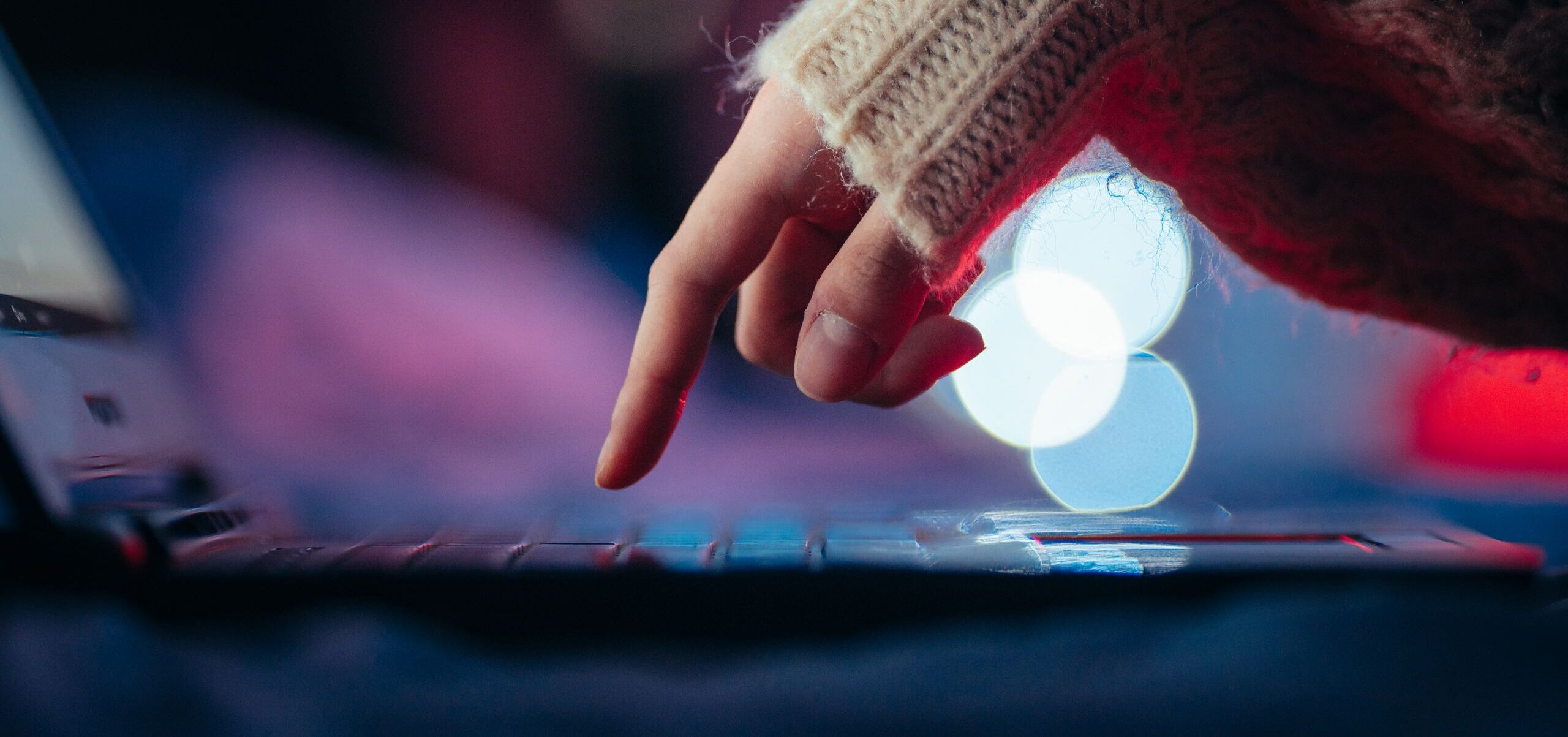 Cozy atmosphere with a hand typing on a laptop surrounded by bokeh lights.